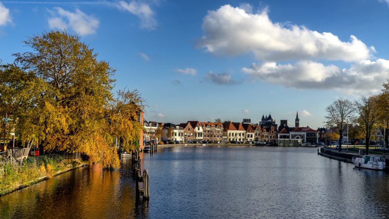 View over the Spaarne river in Haarlem with autumn coloured trees on a beautiful day in november